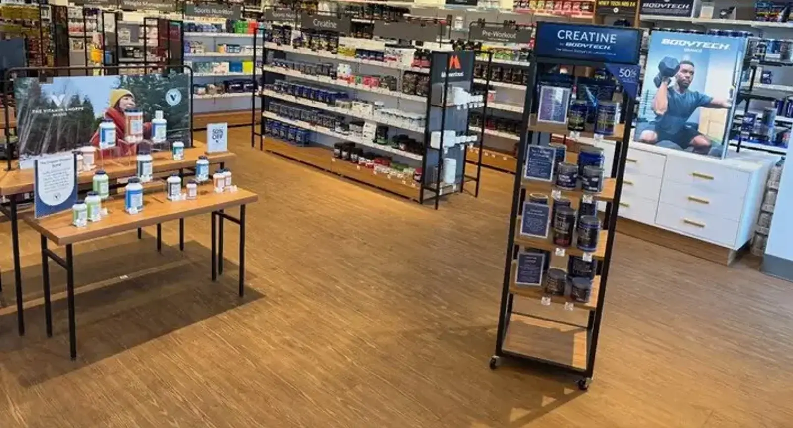 Light wood-look commercial luxury vinyl tile flooring installed by Zona Floors in a retail store sales floor with display tables and product shelving