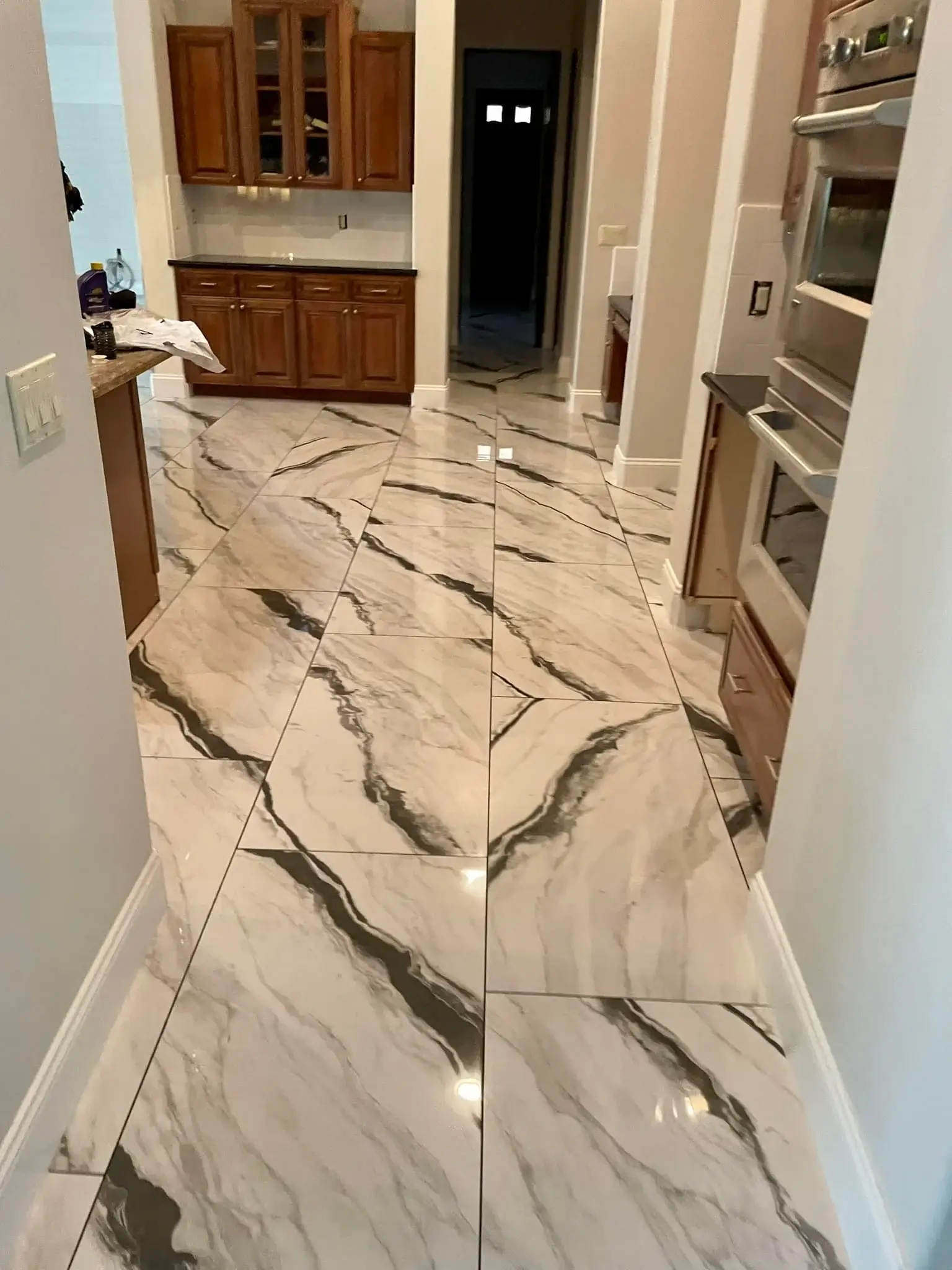 Large-format calacatta-look porcelain tile flooring with dramatic black and gray veining installed by Zona Floors in an Arizona residential kitchen