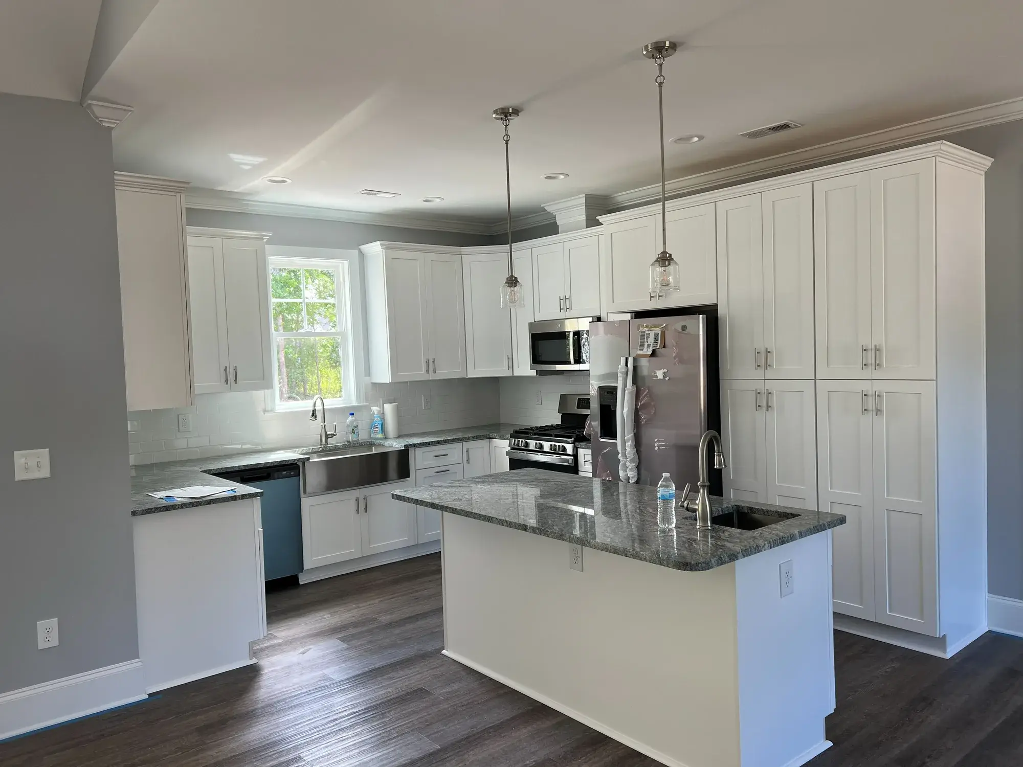 Custom kitchen remodel in Arizona with deep navy shaker cabinets, brass cone pendant lighting, wood lower cabinets, quartz island, and tiled backsplash by Zona Floors