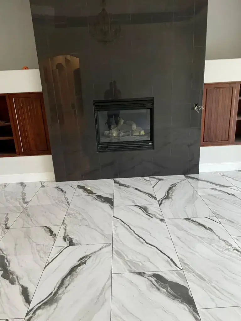 Custom dark tile fireplace surround above large-format marble-veined porcelain tile flooring installed by Zona Floors in Arizona